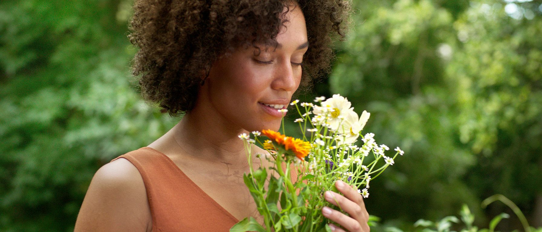 Frau in der Natur riecht an Blumen