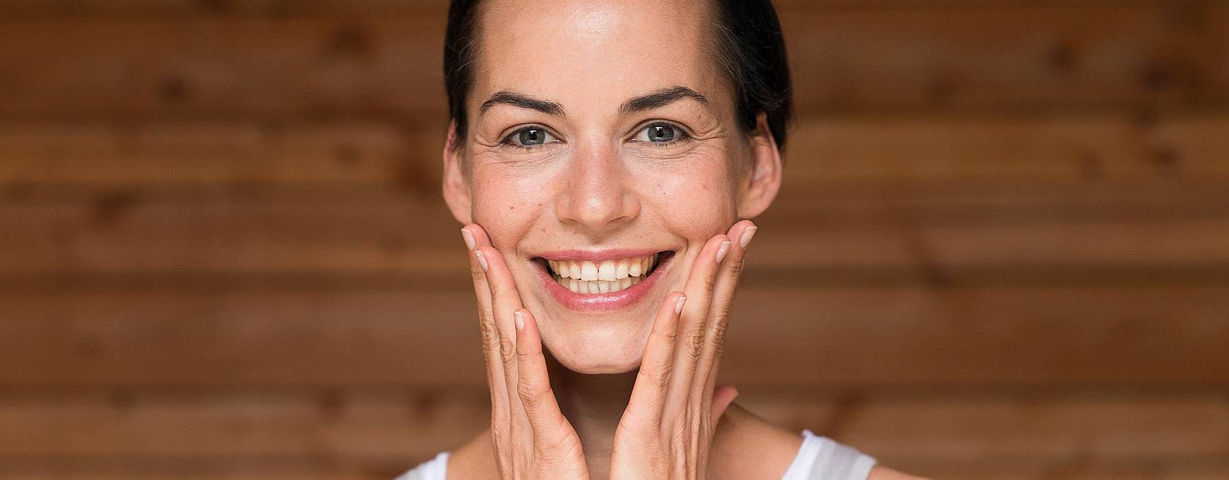 lachende frau hält beide hände ans gesicht