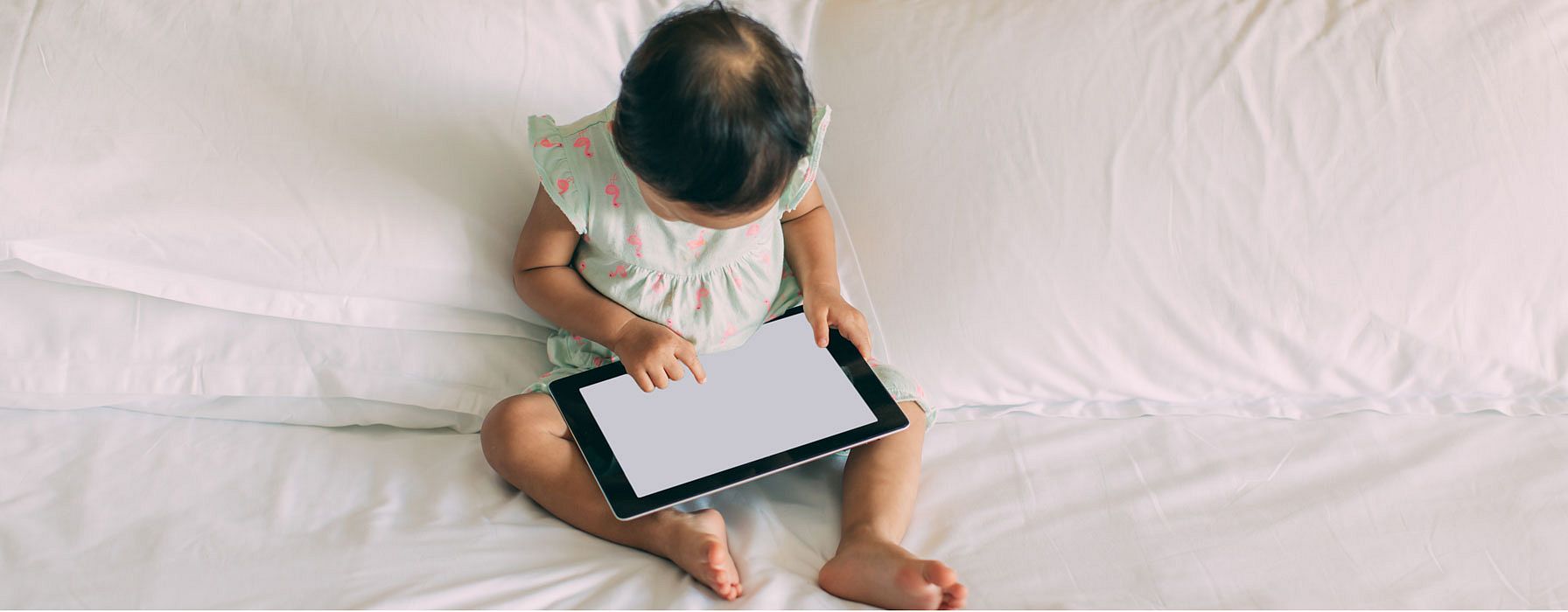 Kind sitzt vor einem Tablet Bildschirm