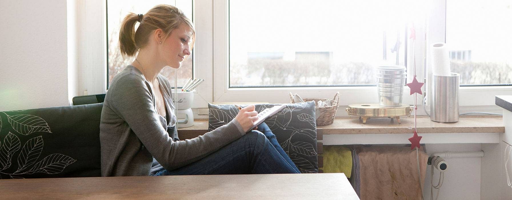 Frau auf dem Sofa macht sich Notizen