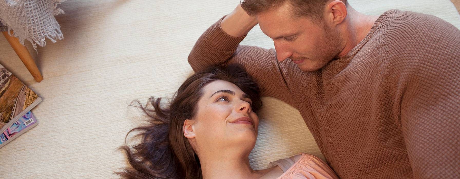 Glückliches Paar auf dem Teppichboden liegend