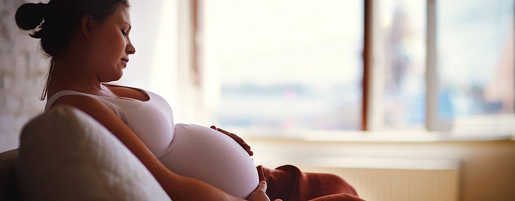 Schwangere legt Hand auf Bauch