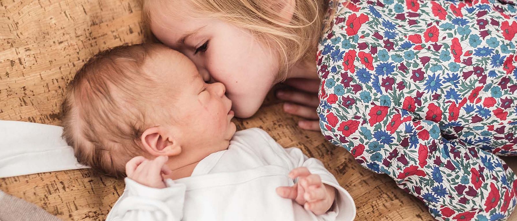 Ältere Schwester küsst Baby
