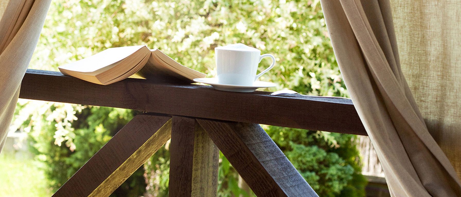 Buch, Tasse Tee am Fenster mit Blick auf die Natur draußen