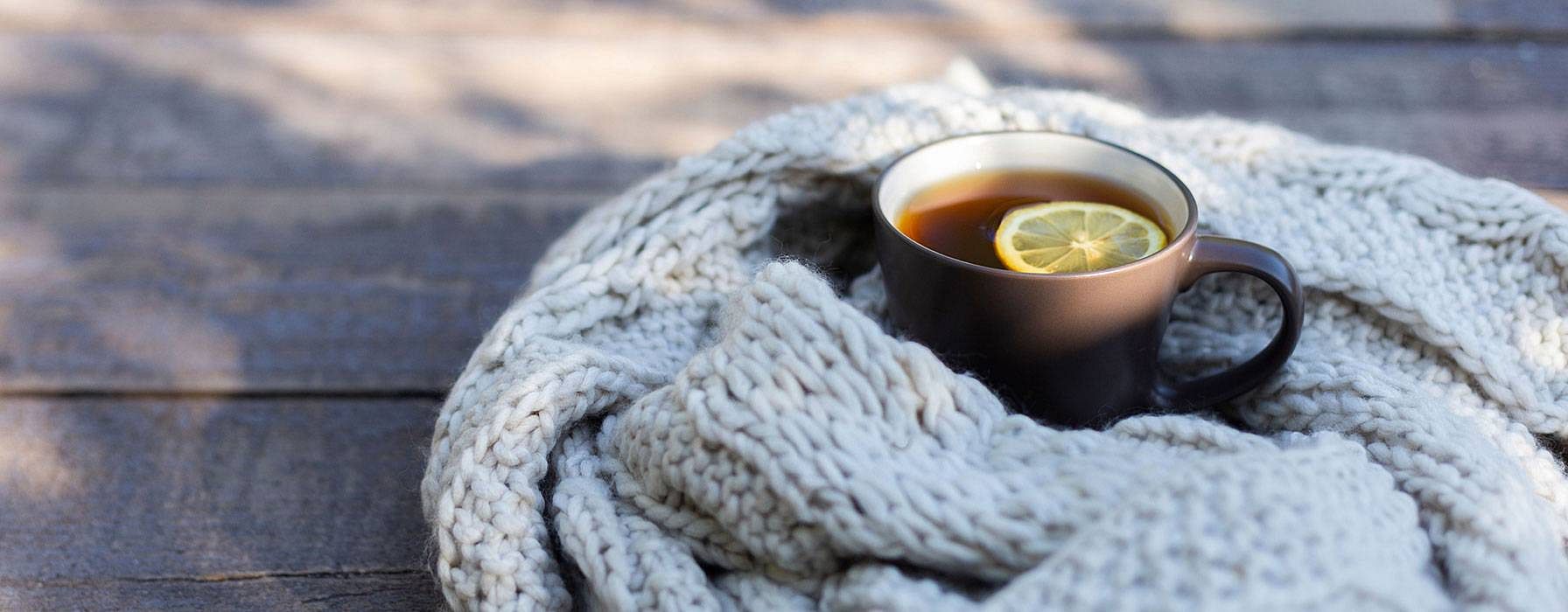 Schal und eine Tasse Tee mit Zitrone