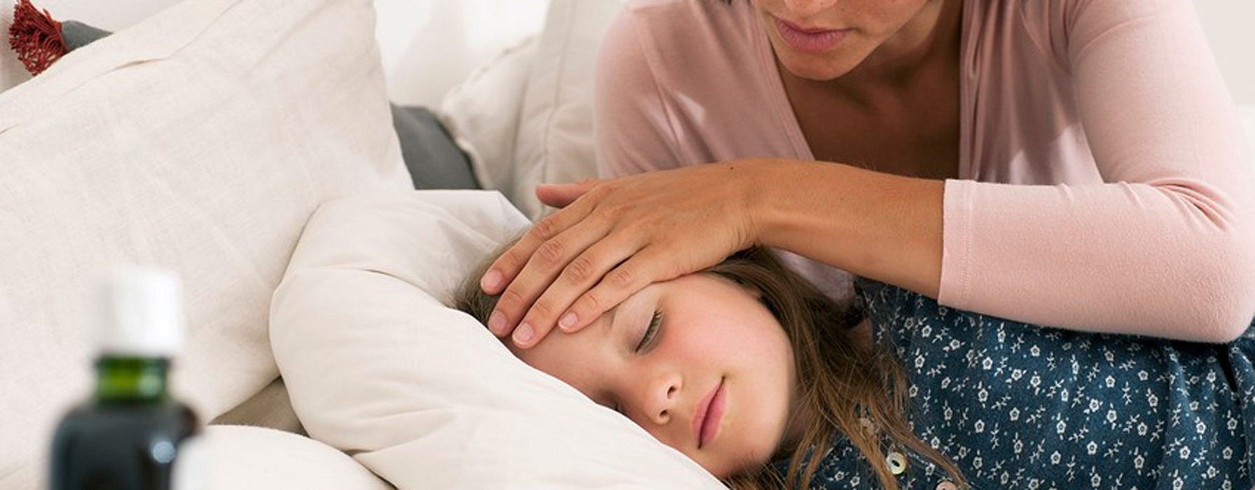 Frau umsorgt krankes Kind im Bett