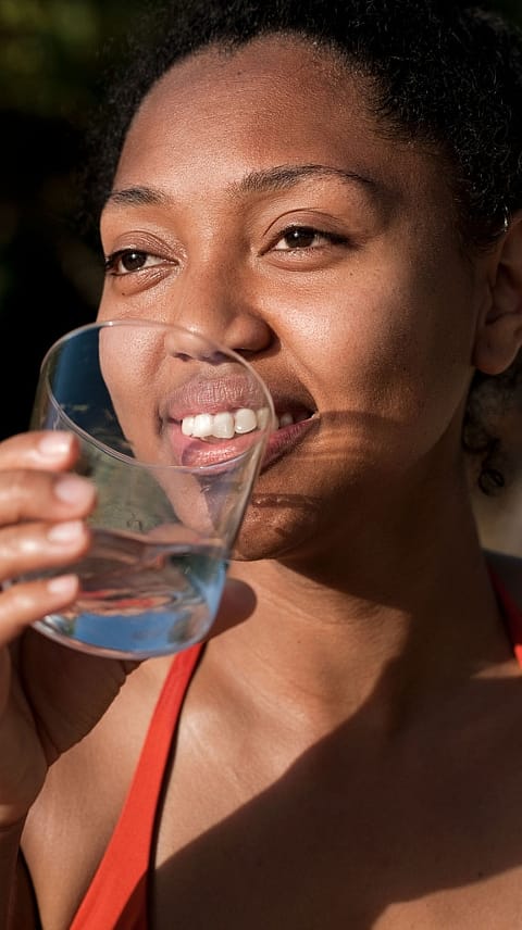 Frau trinkt aus Wasserglas