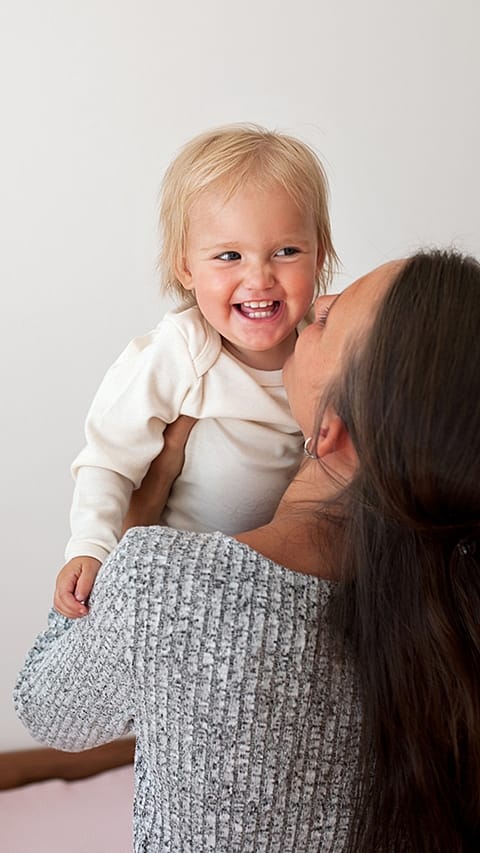 Mutter hebt lachendes Kind hoch
