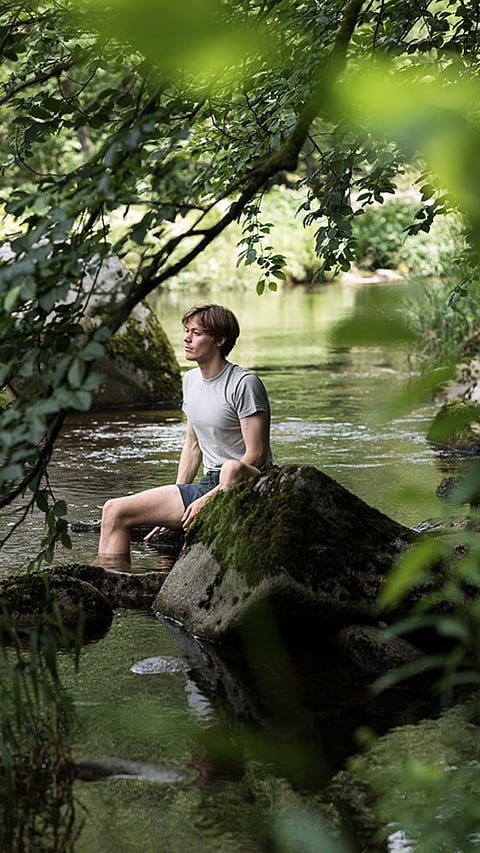 Mann am Fluss umgeben von Wald