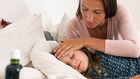 Frau umsorgt krankes Kind im Bett