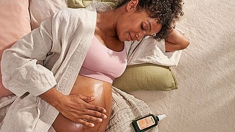 Schwangere Frau massiert sich den Bauch