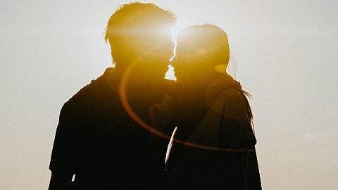 Eine Frau und ein Mann kuessen sich im Gegenlicht