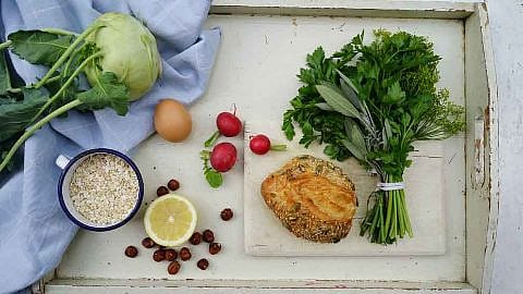 Auf einem Tablett liegen ein Broetchen, ein Ei, Kohlrabi und Kraeuter als Zutaten fuer den Burger