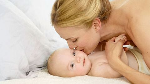 Mutter küsst nacktes Kind
