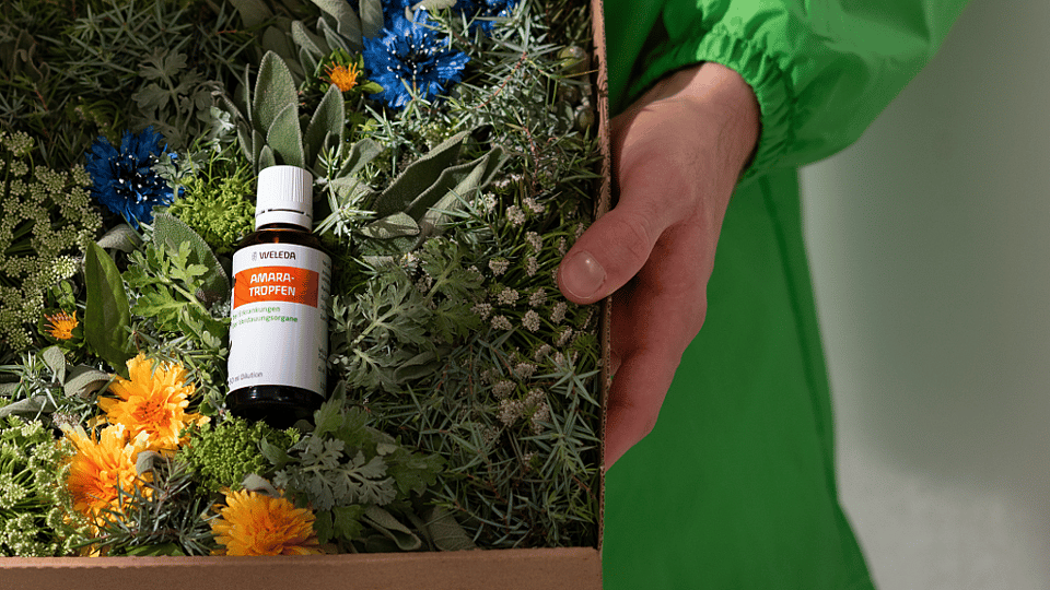 woman with beige pullunder holding amara-drops in her hand