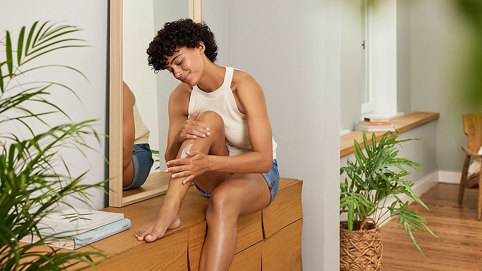 Frau cremt Beine ein