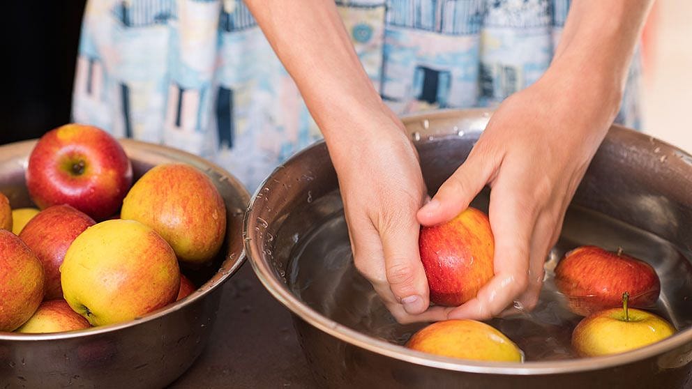 Frau waescht Aepfel in einer Schuessel