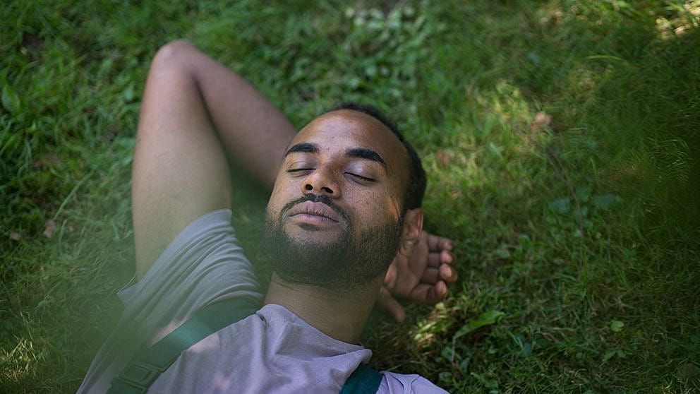 Mann liegt schlafend im Gras
